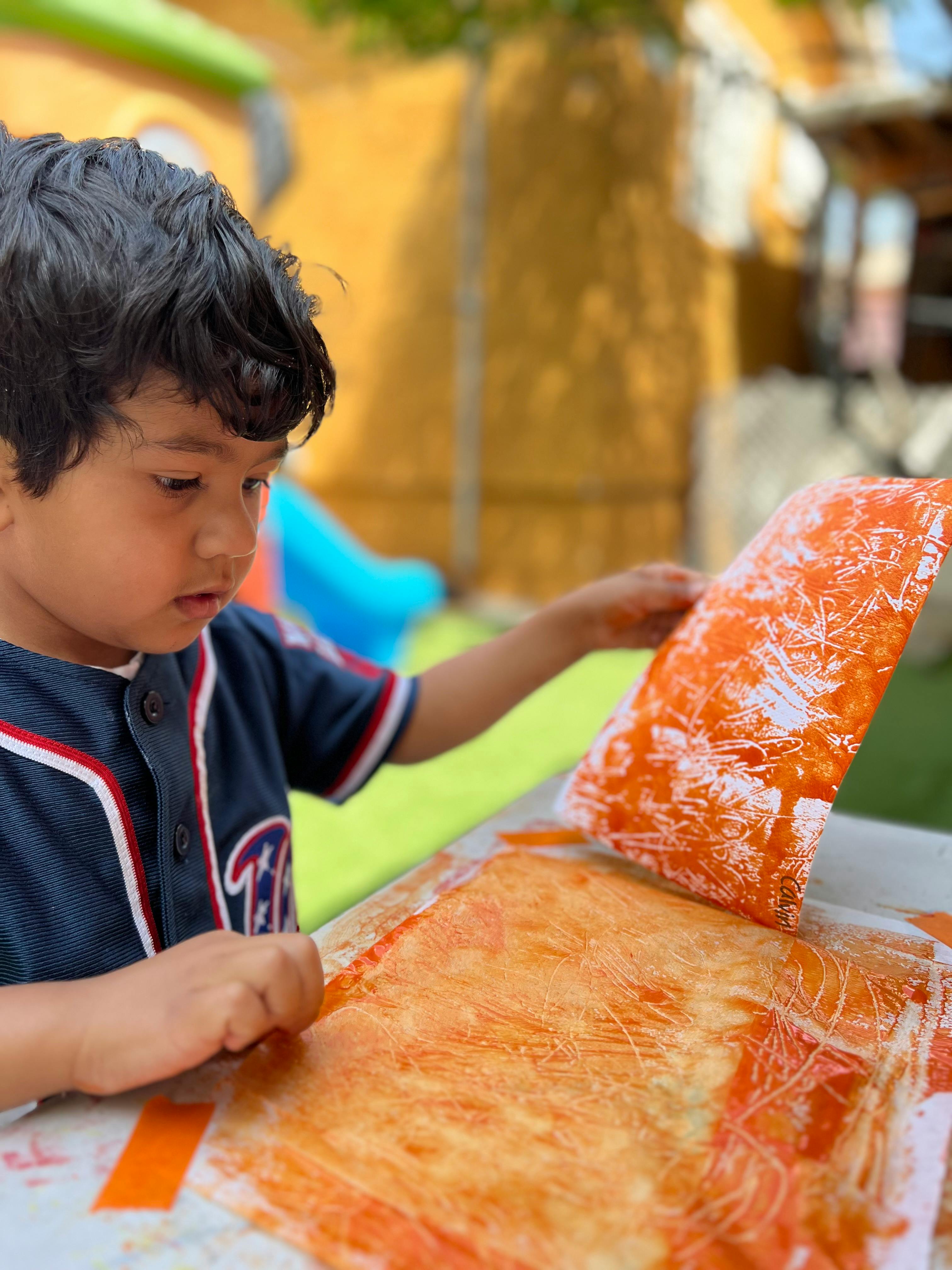 Child peeling painted paper from a surface