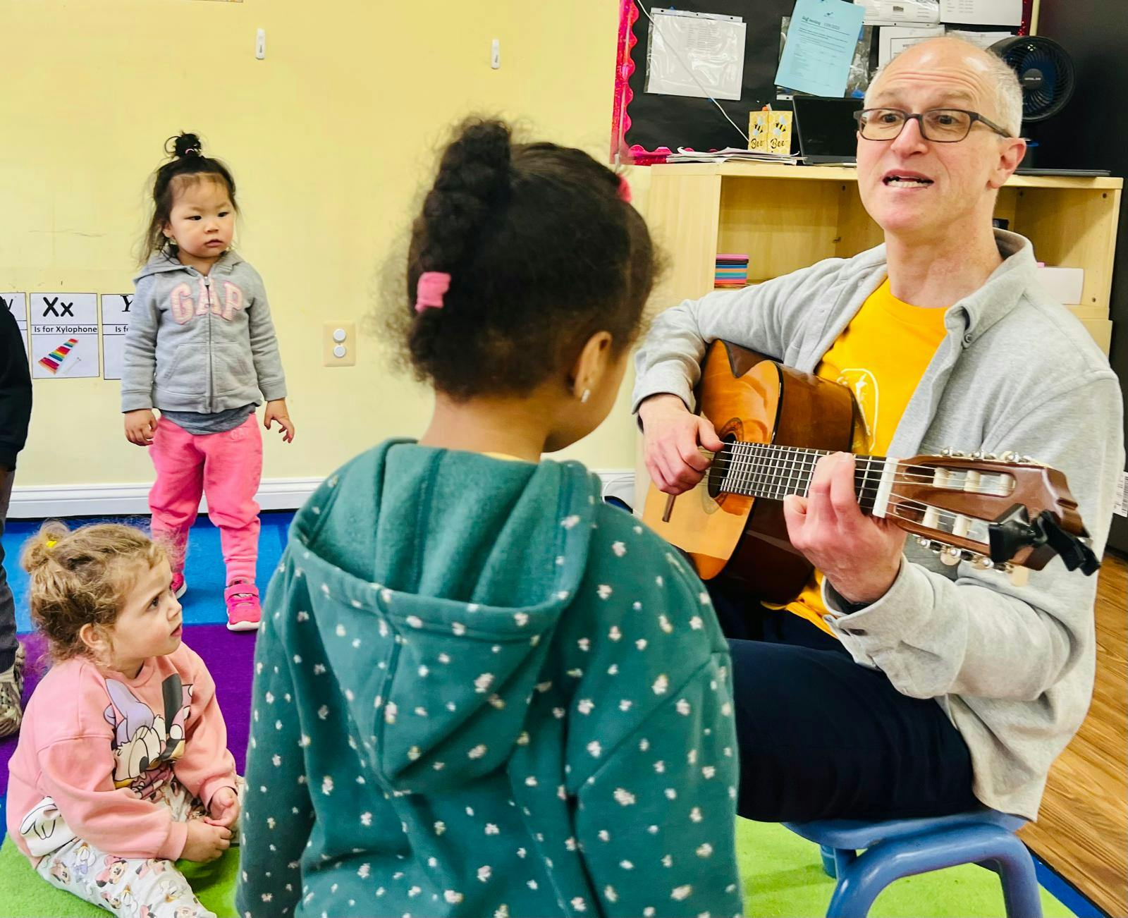 Adult playing guitar for children in a classroom