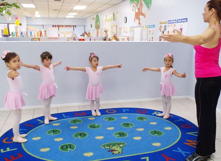 Adult and children in pink outfits with arms outstretched