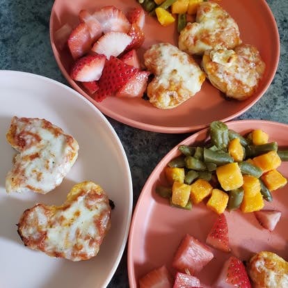 Three plates of food with heart-shaped items, strawberries, and vegetables