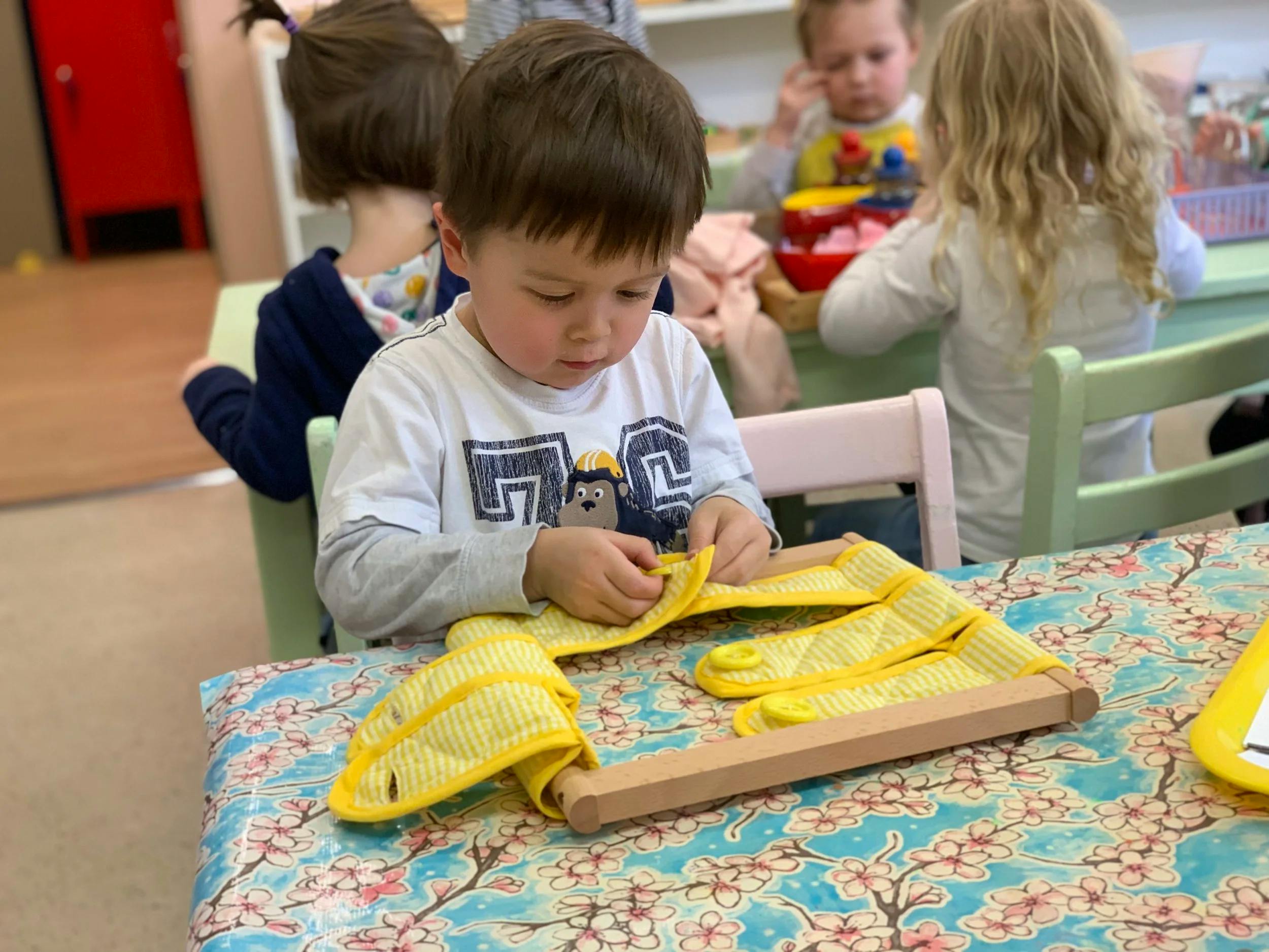 Child learning to button clothes with a Montessori dressing frame
