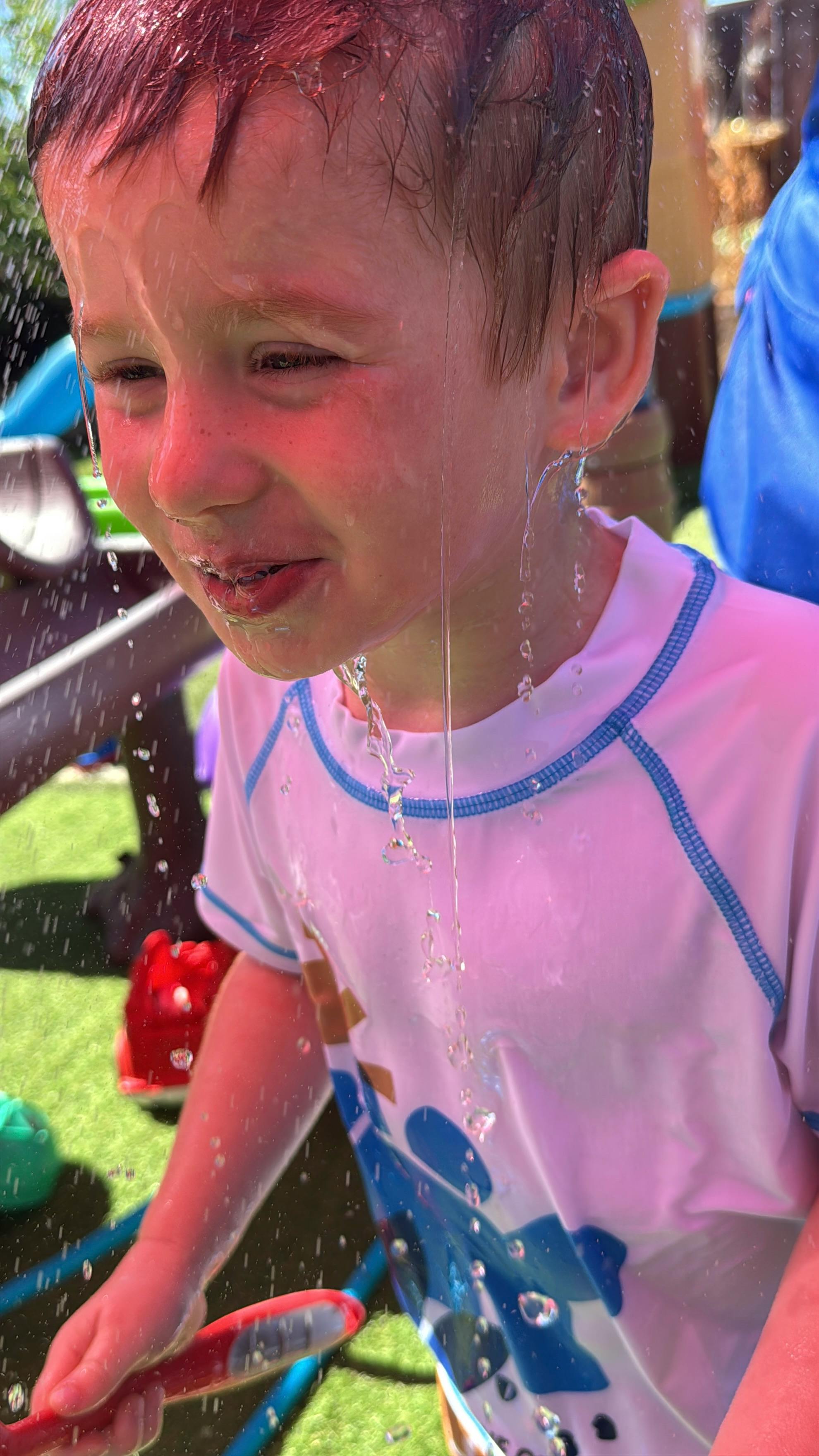 Child standing under falling water outdoors