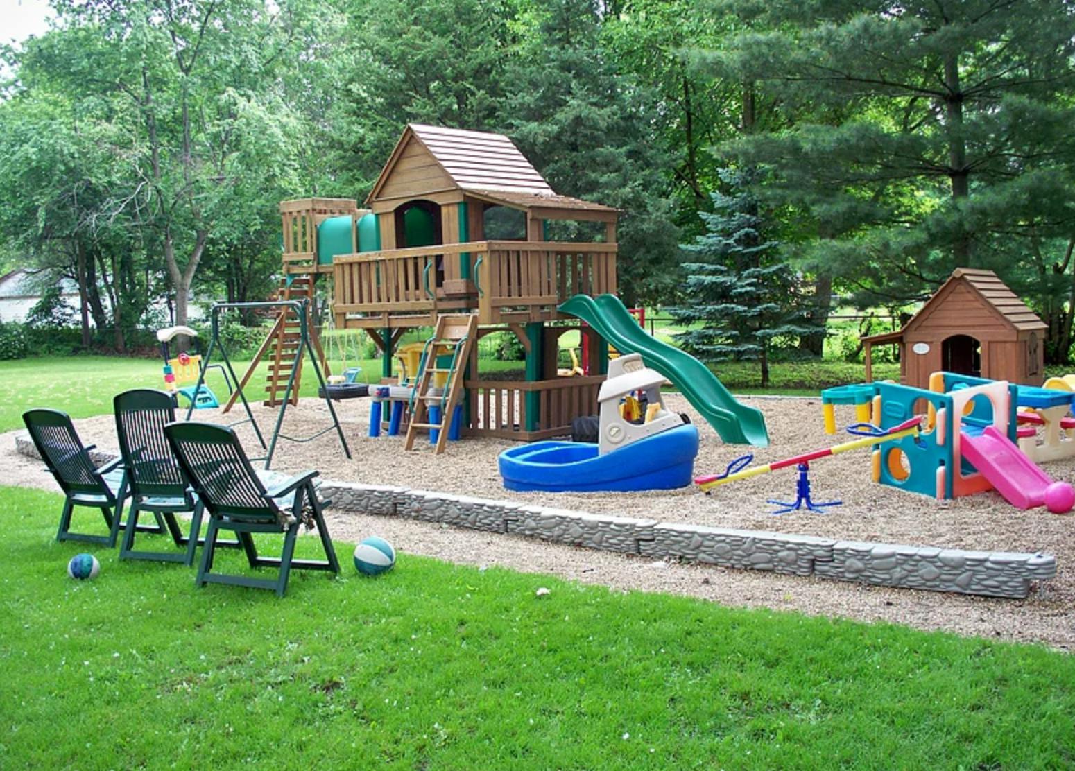 Outdoor playground with wooden playset, slides, swings, and plastic play structures