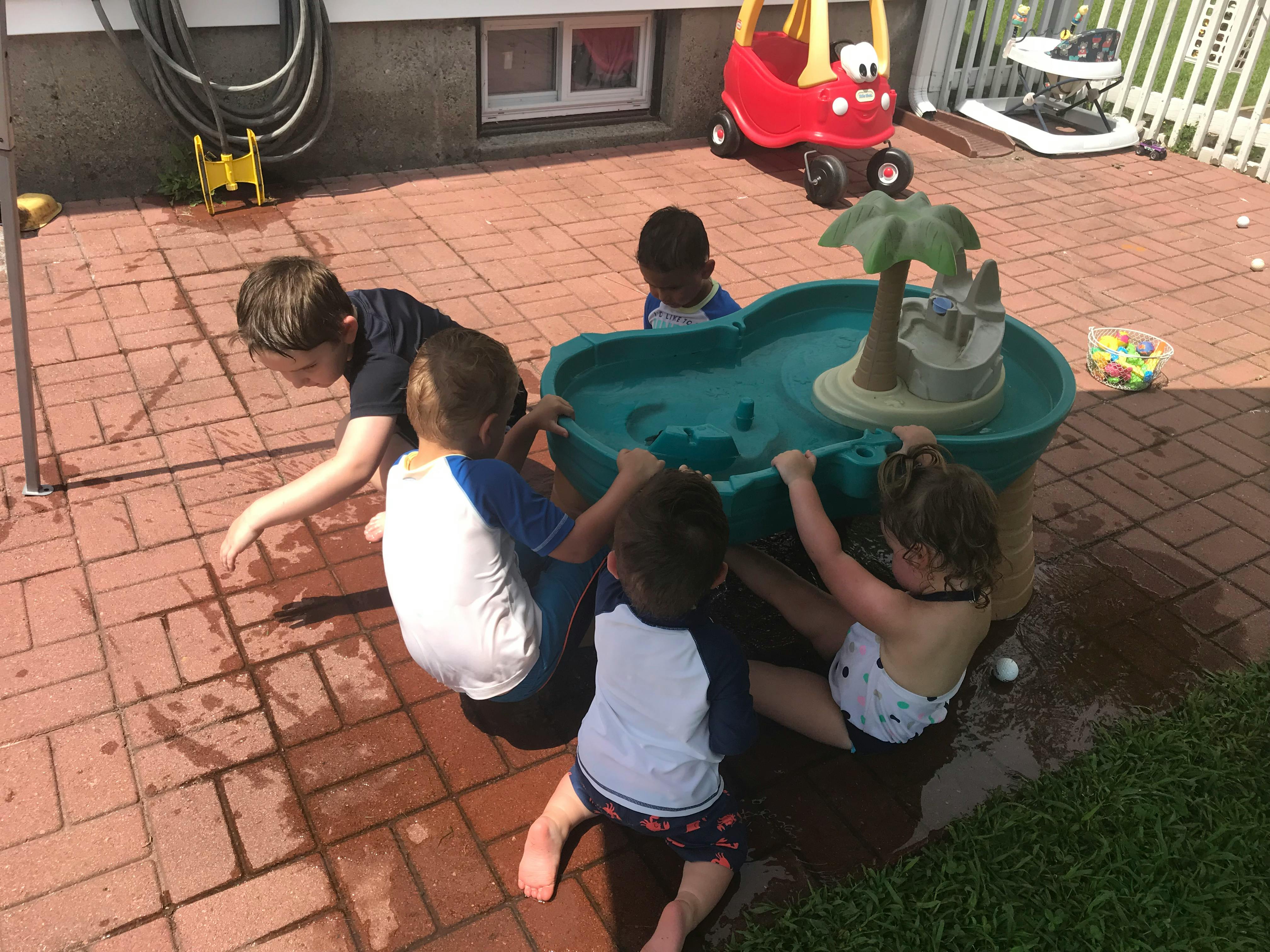 Children playing with a water table on a patio