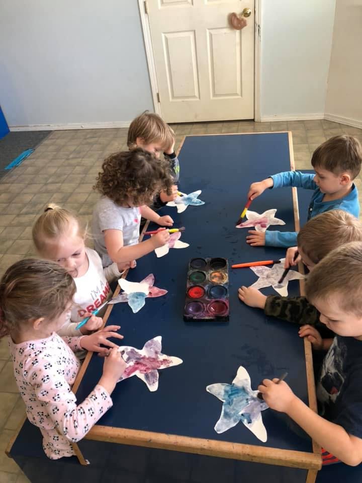 Children painting star-shaped cutouts at a table
