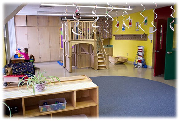 Child playing in a classroom with a wooden play structure