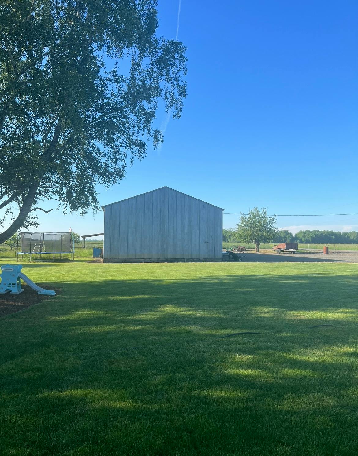 A large metal building in a grassy field under a clear sky