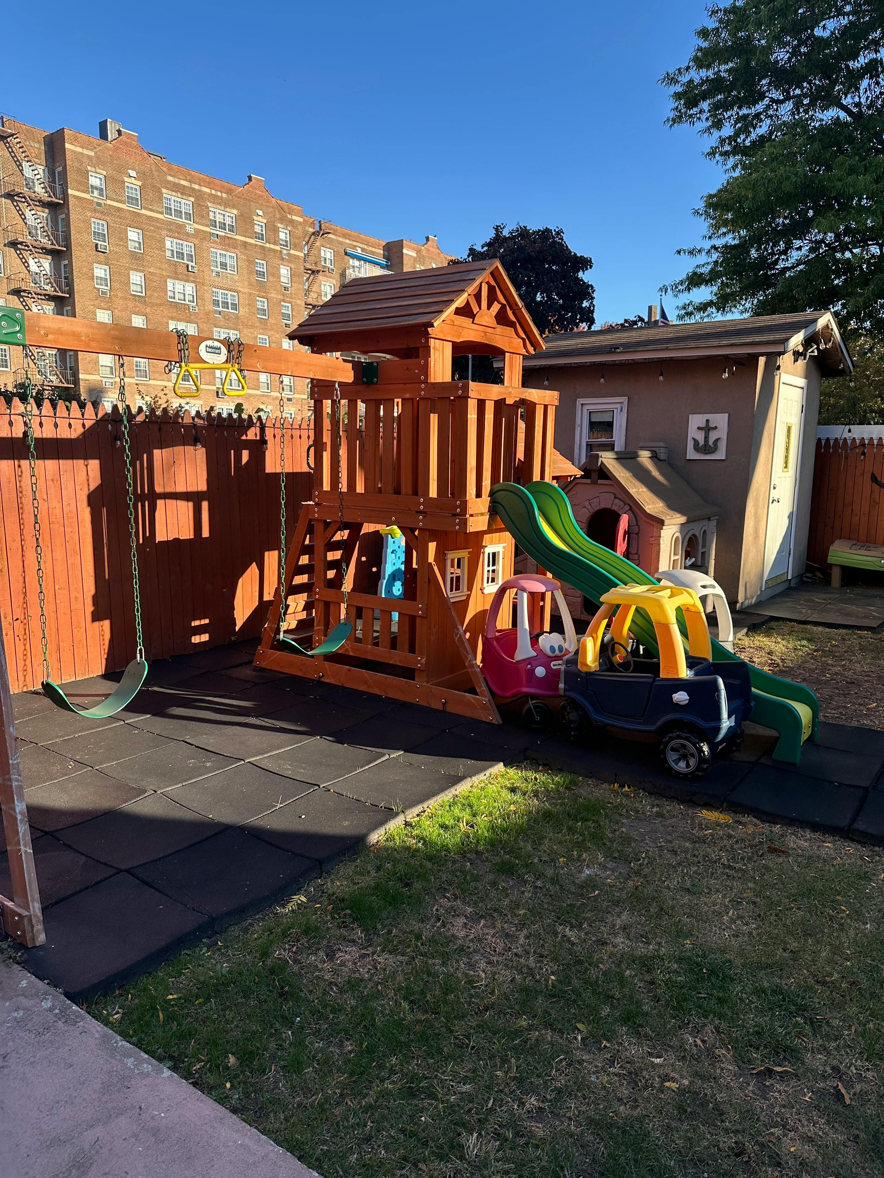 Wooden playground set with swings, slide, and toy cars