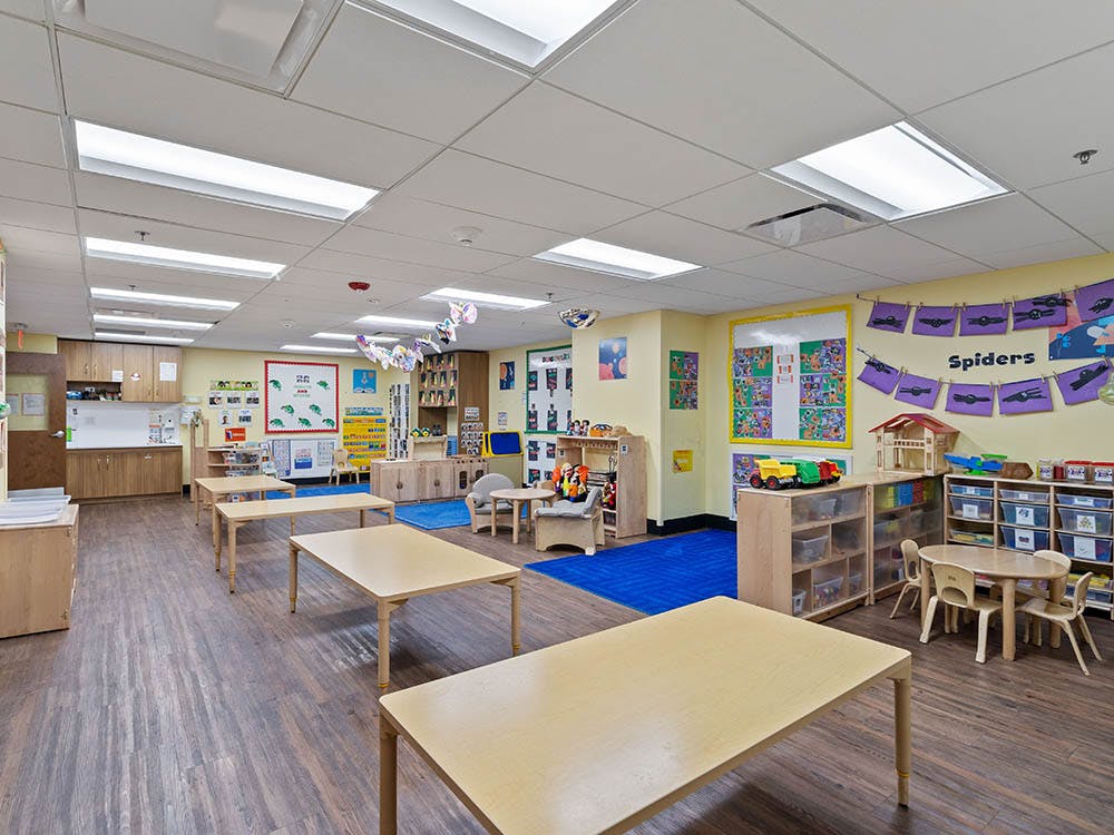 Empty classroom with small tables and chairs, and bright decorations