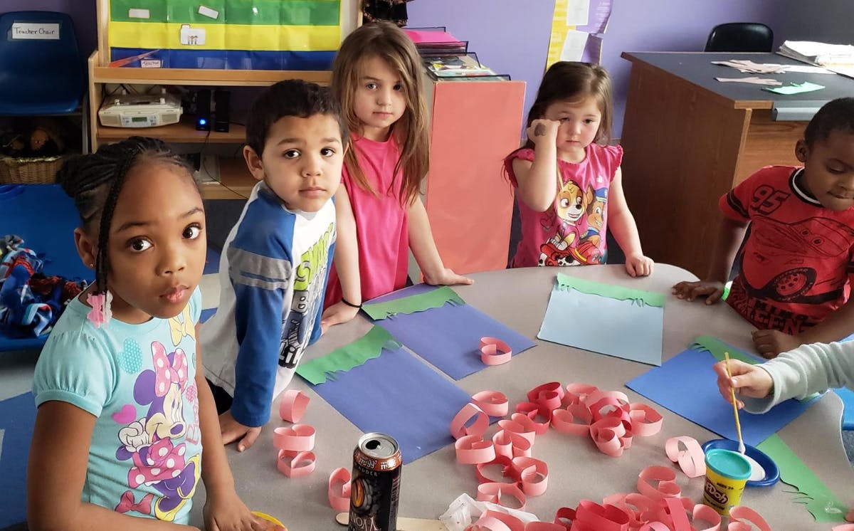 Children gathered around a table with craft supplies