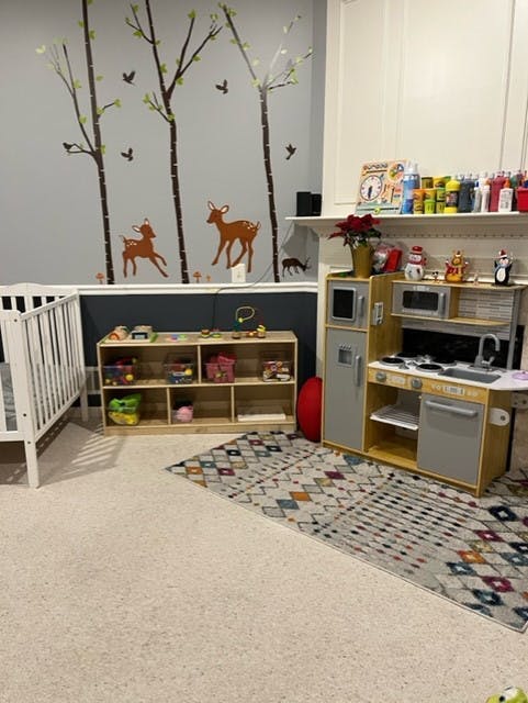 Playroom with a crib, toy kitchen, and deer wall decals