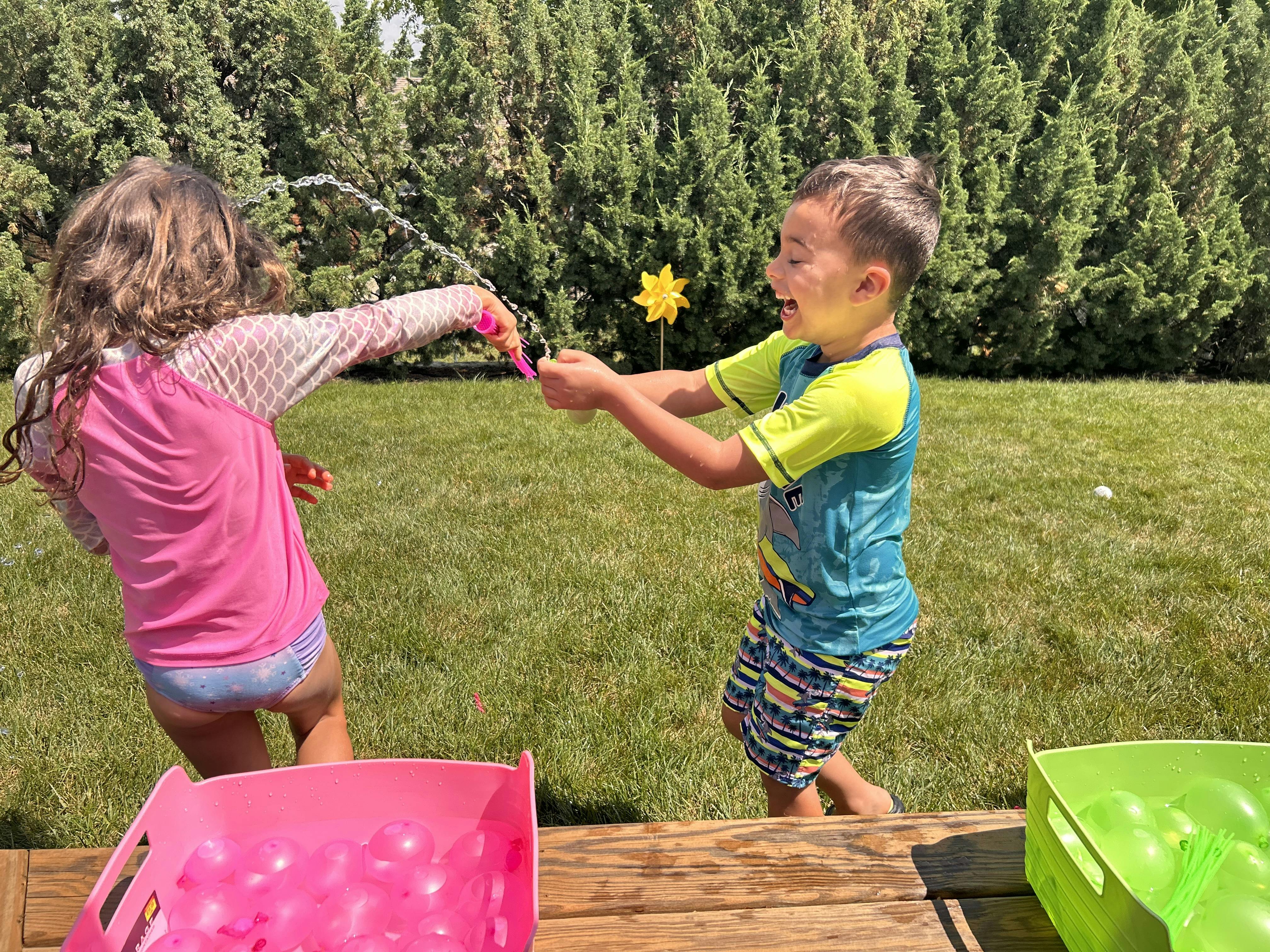 Children playing with water balloons on a sunny lawn