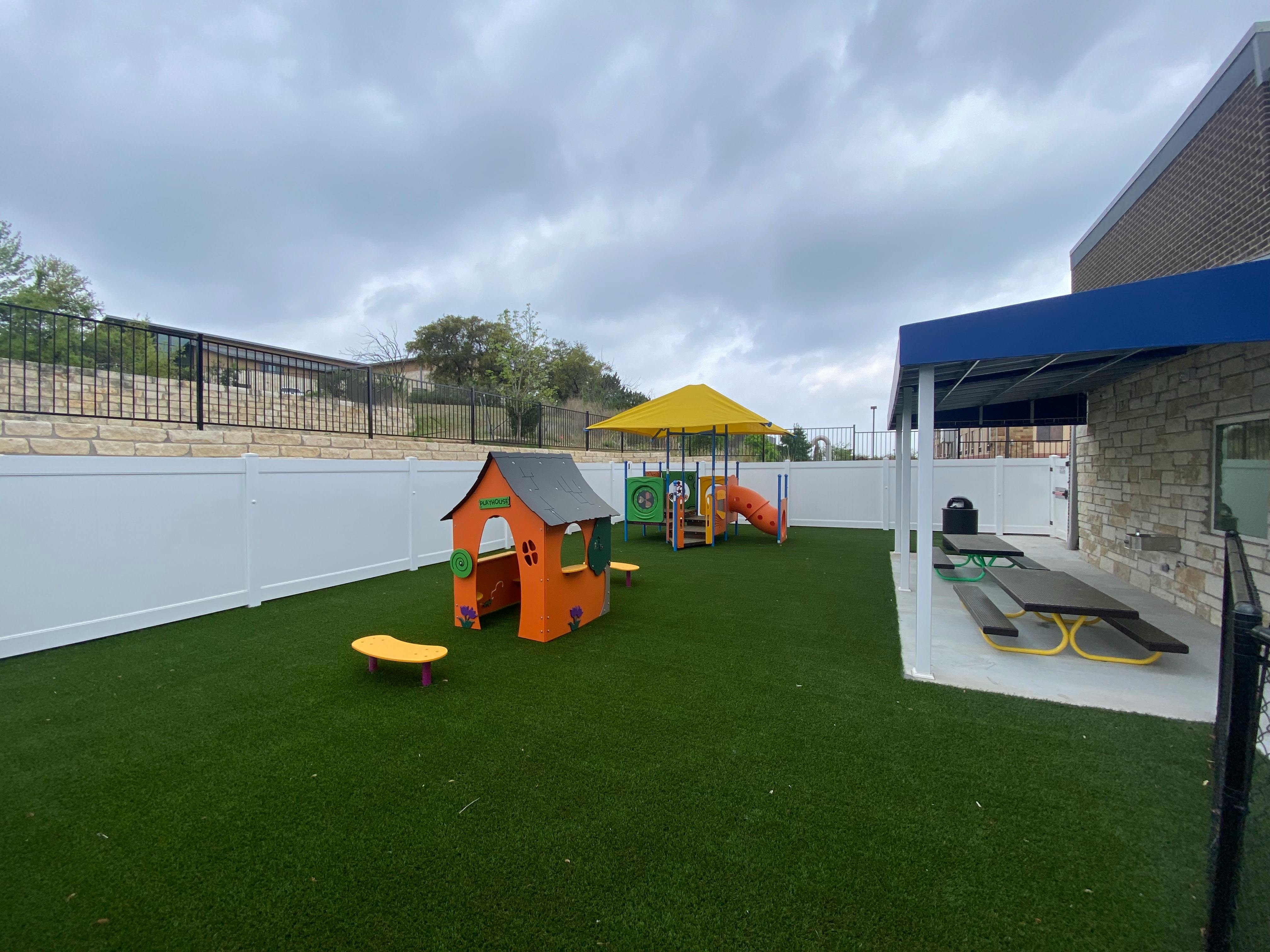 Outdoor playground with playhouse, slide, and picnic tables
