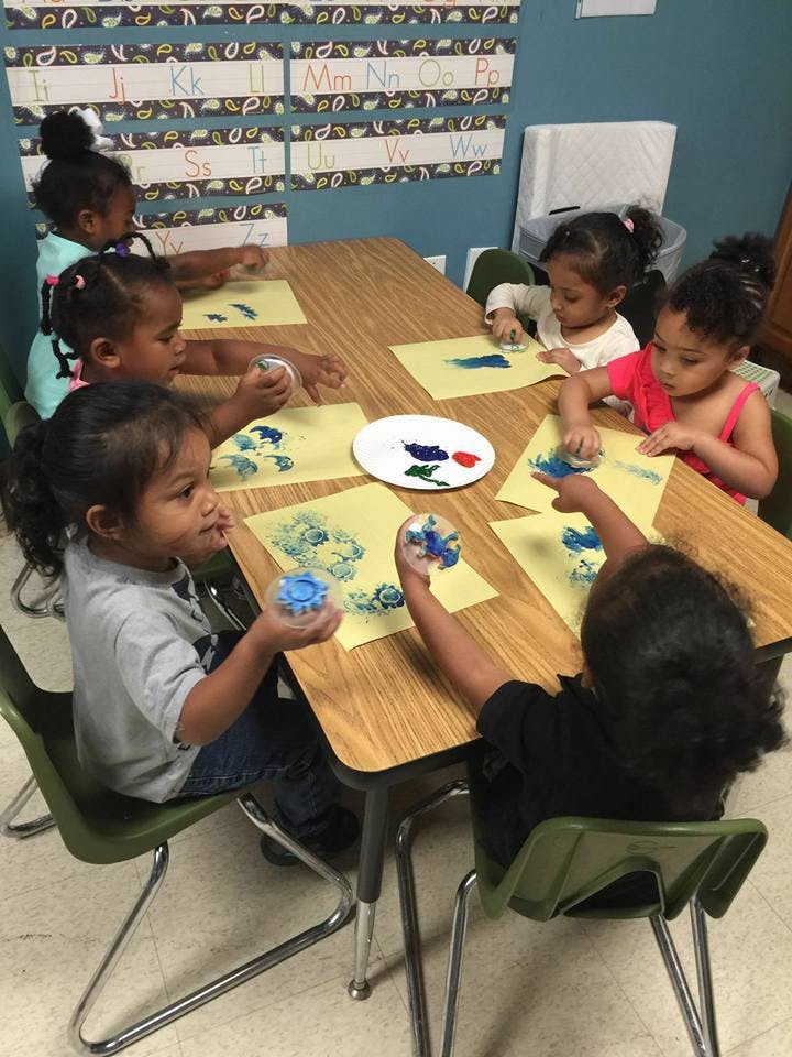 Children painting at a table in a classroom