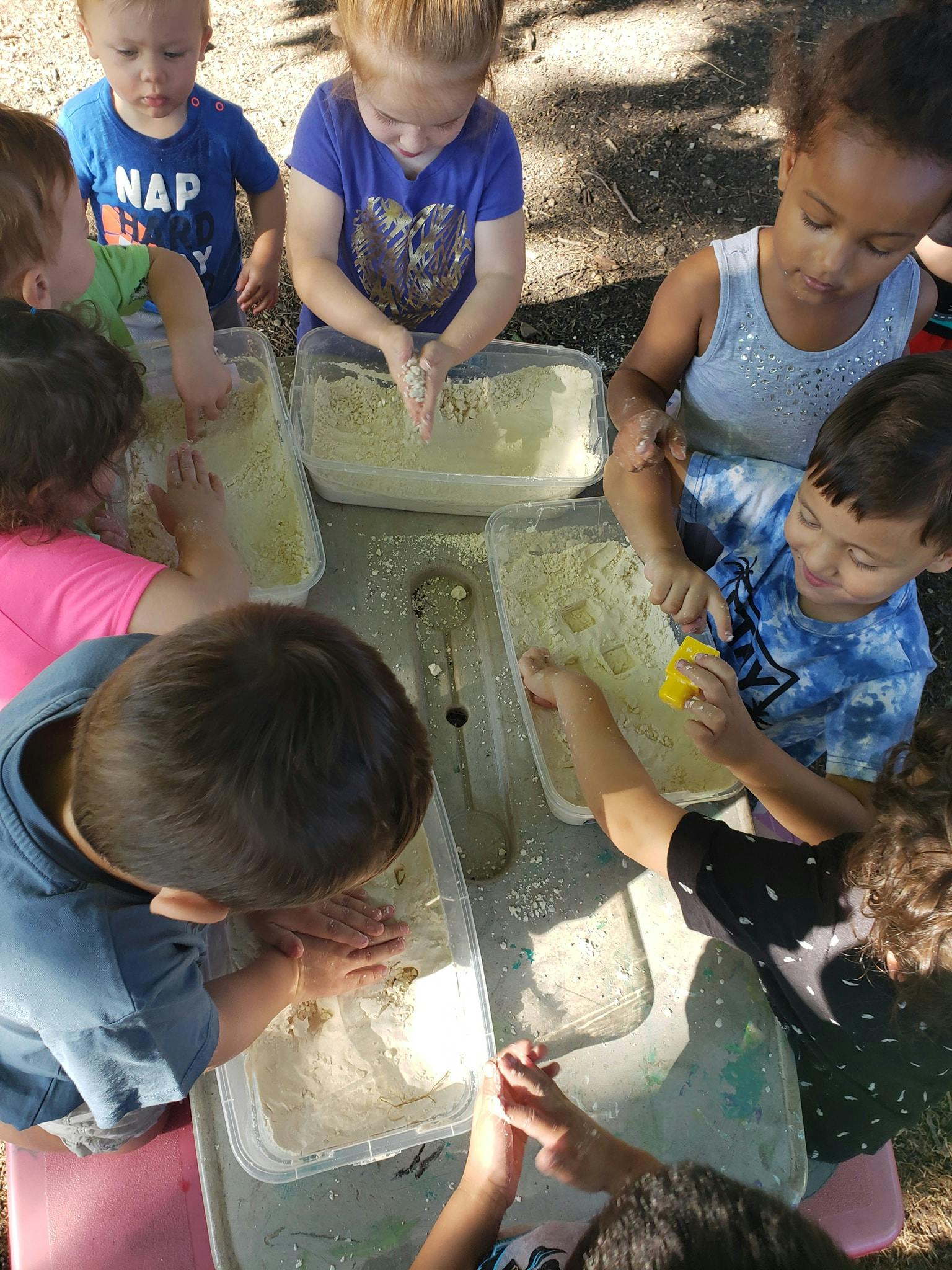 Children playing with sensory bins outdoors