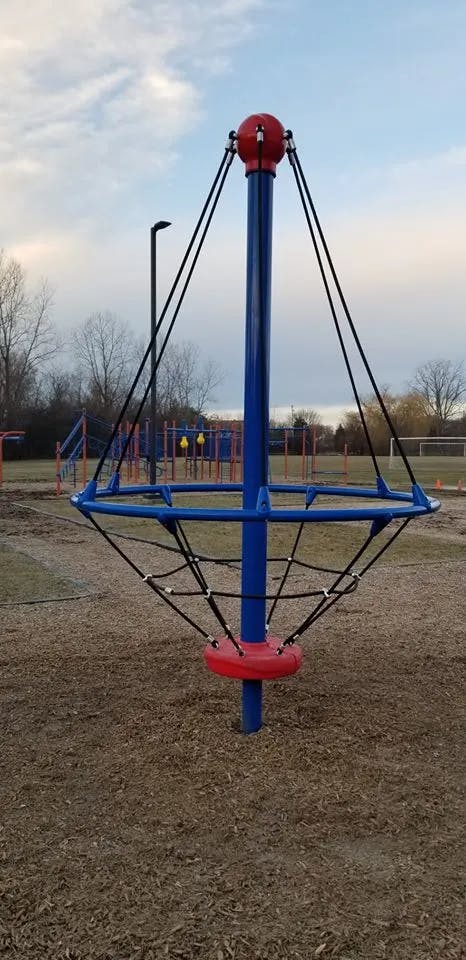 Playground equipment with a central blue pole and red spherical top