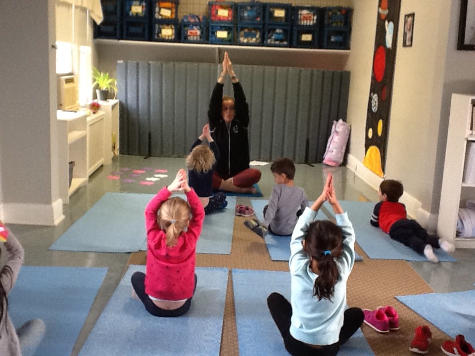 Adult and children doing yoga poses on mats in a room