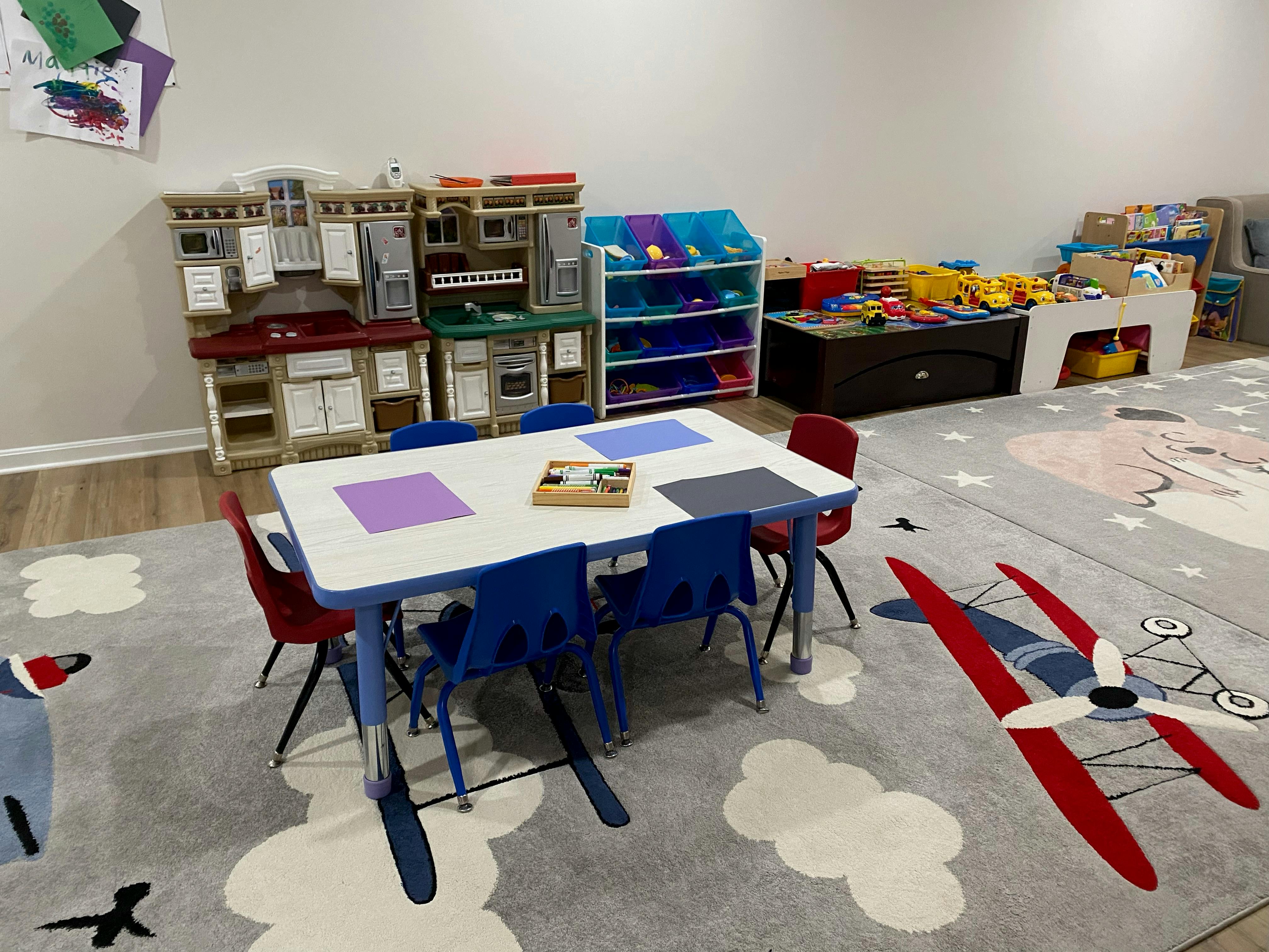 Playroom with a table and chairs, toy kitchen, and storage shelves