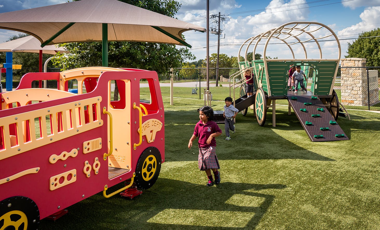 Child playing on a playground with a fire truck and wagon structure
