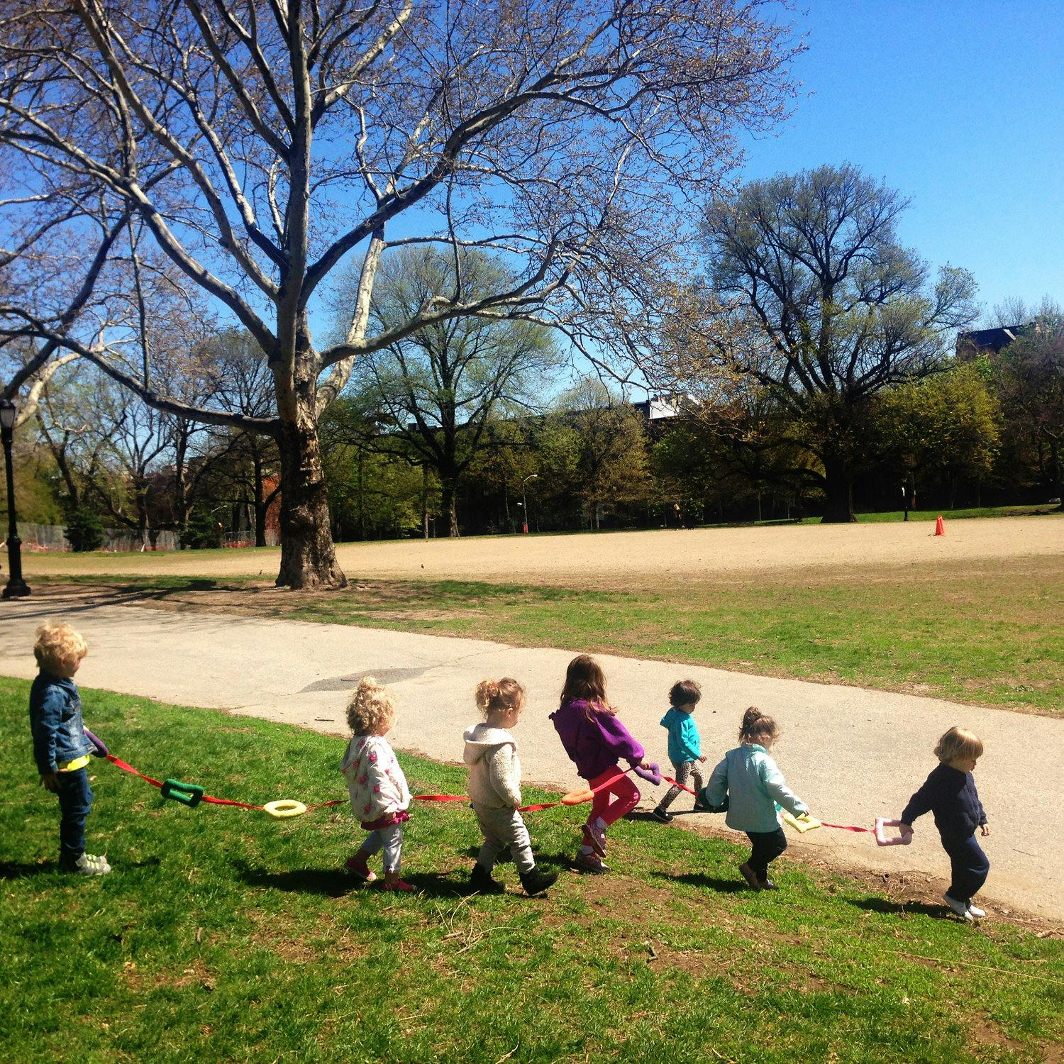 Children walking in a line on a leash in a park