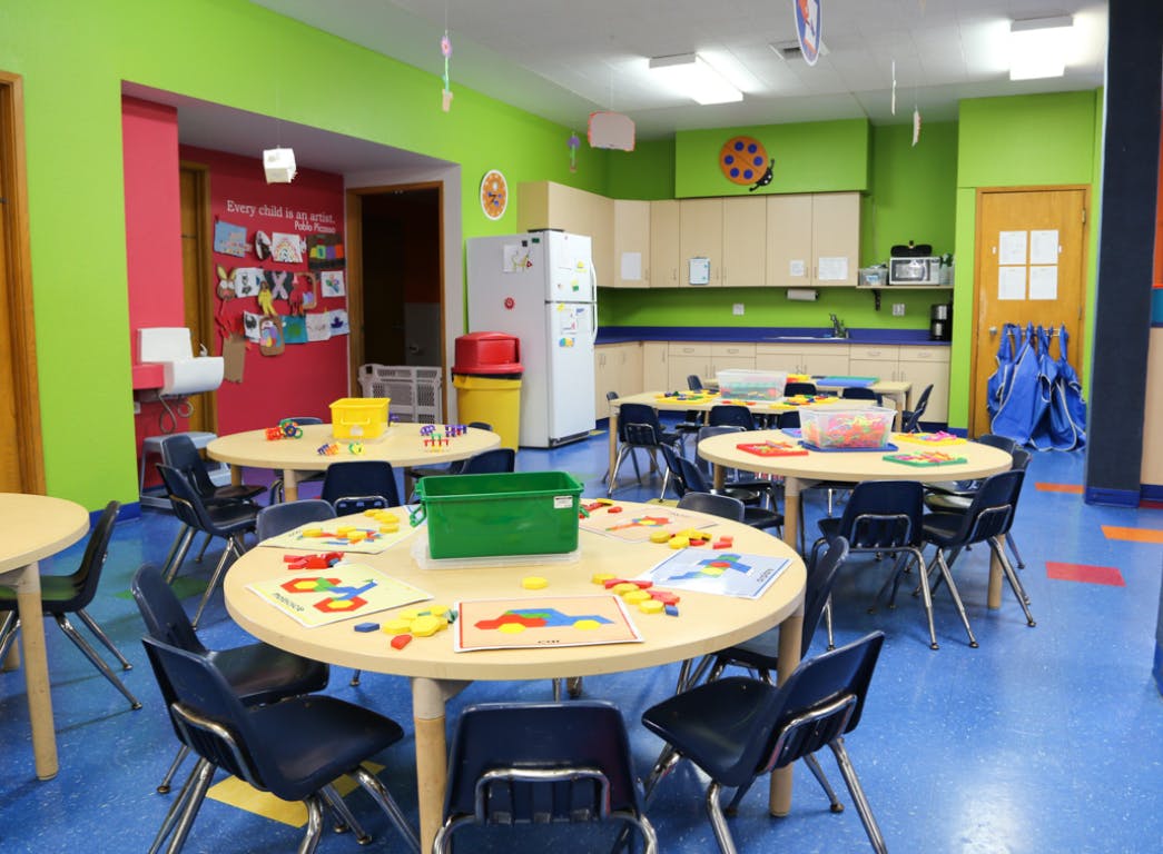 Classroom with round tables and chairs, a kitchen area, and colorful walls