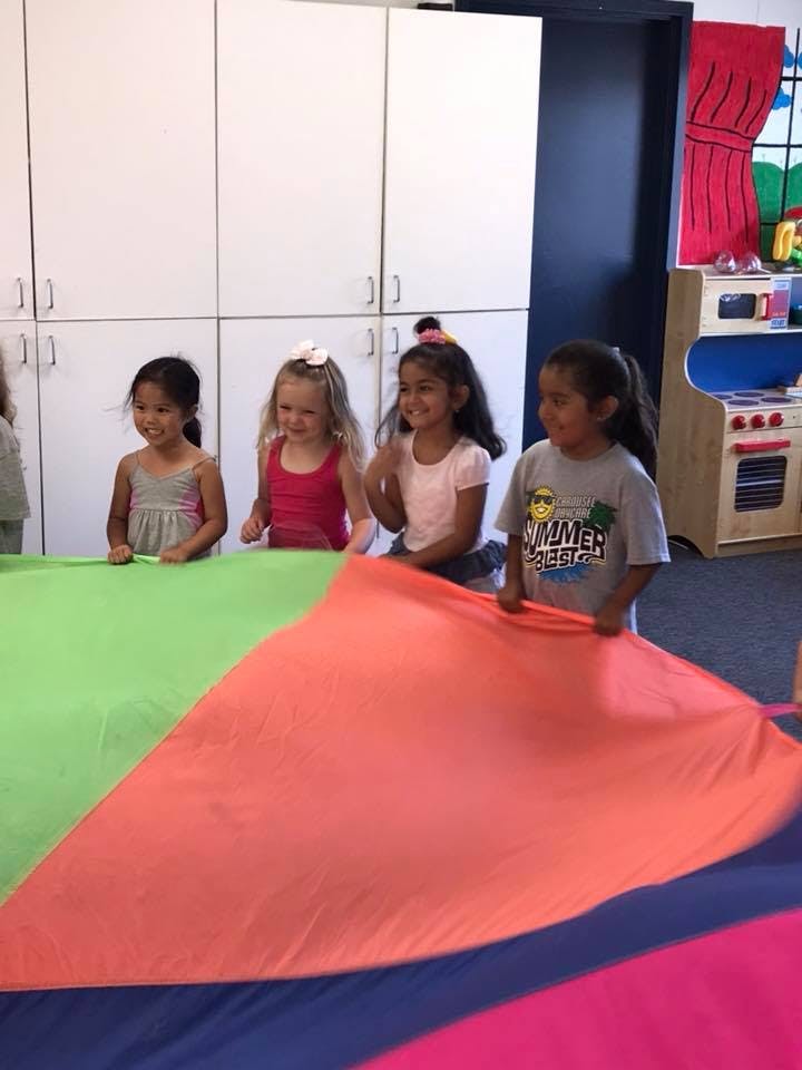 Four children playing with a colorful parachute