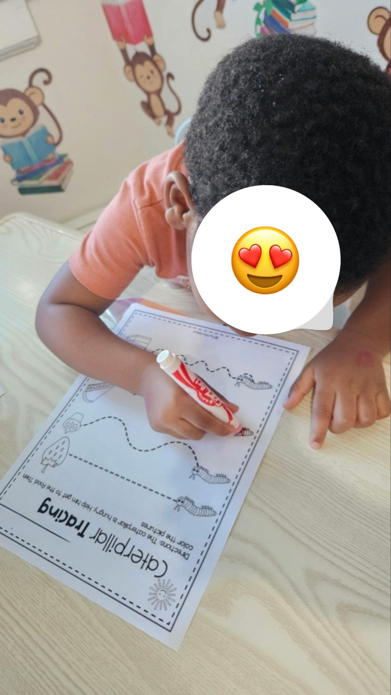 Child tracing lines on a "Caterpillar Tracing" worksheet with a marker