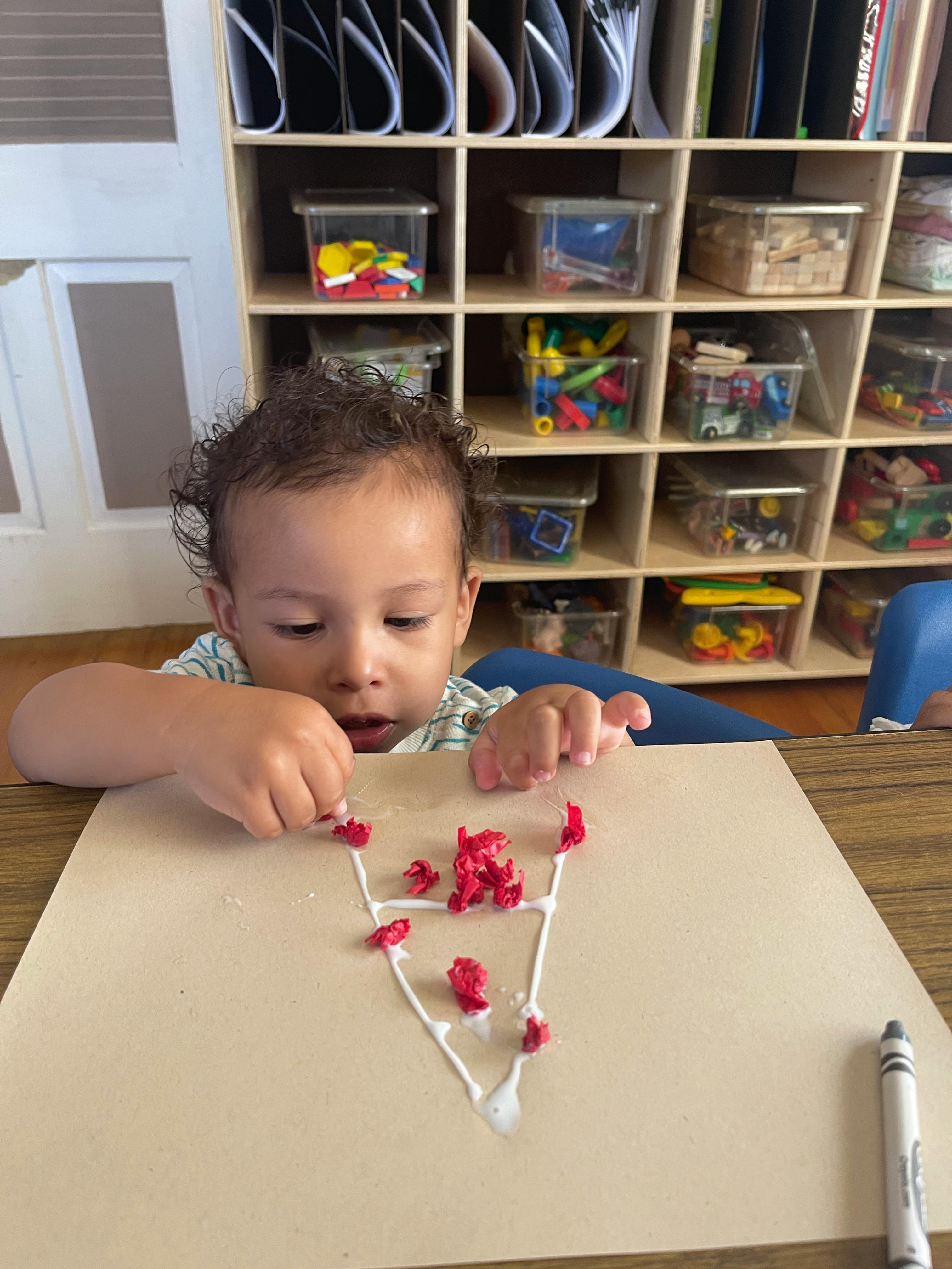 Child doing an art project with glue and red pieces