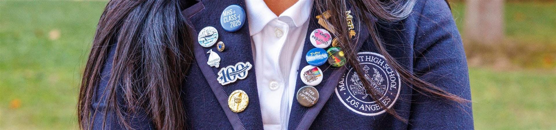 Close-up of a person wearing a blazer adorned with numerous pins