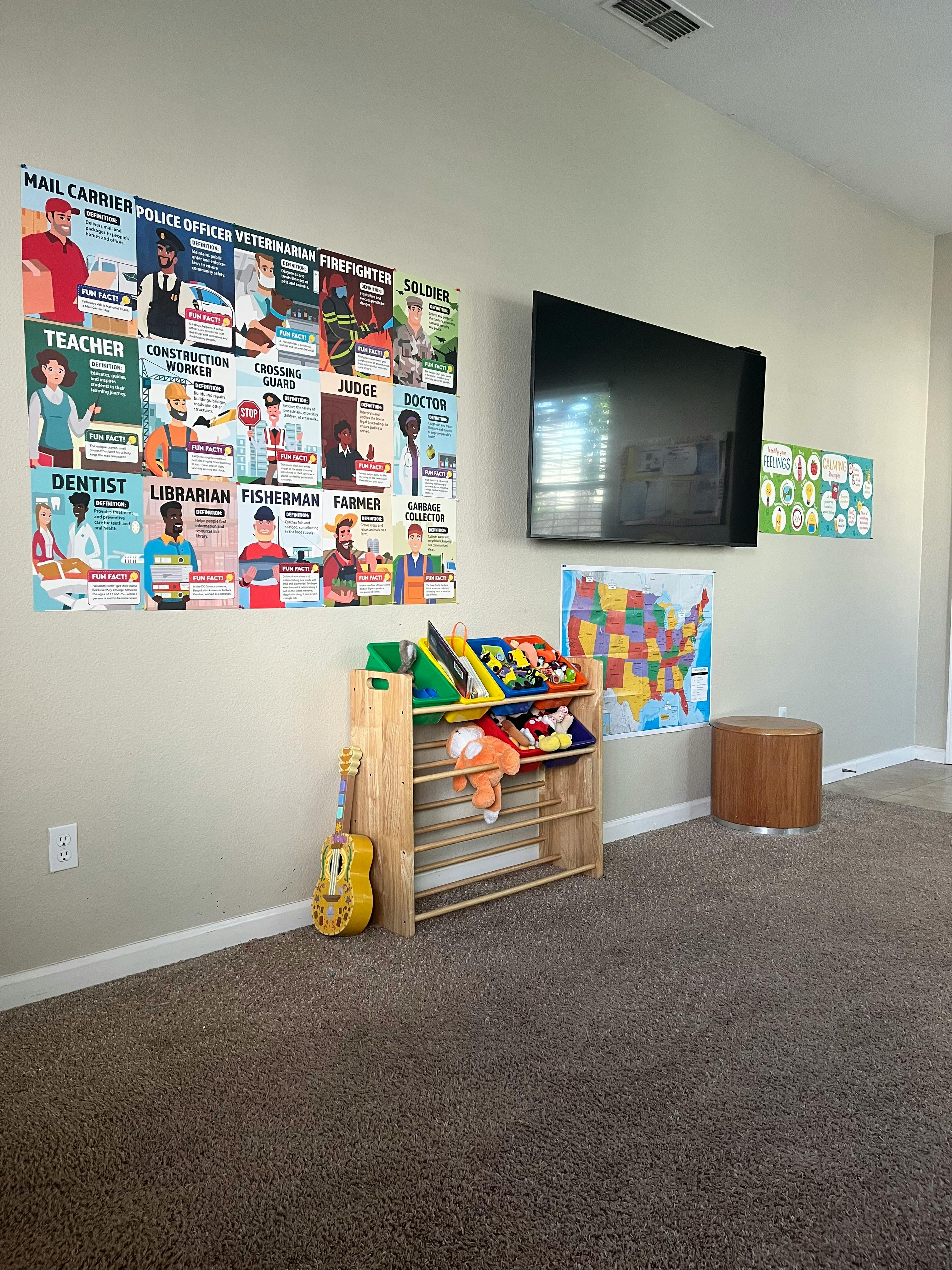 Wall with a large poster of various occupations, a TV, and a toy shelf