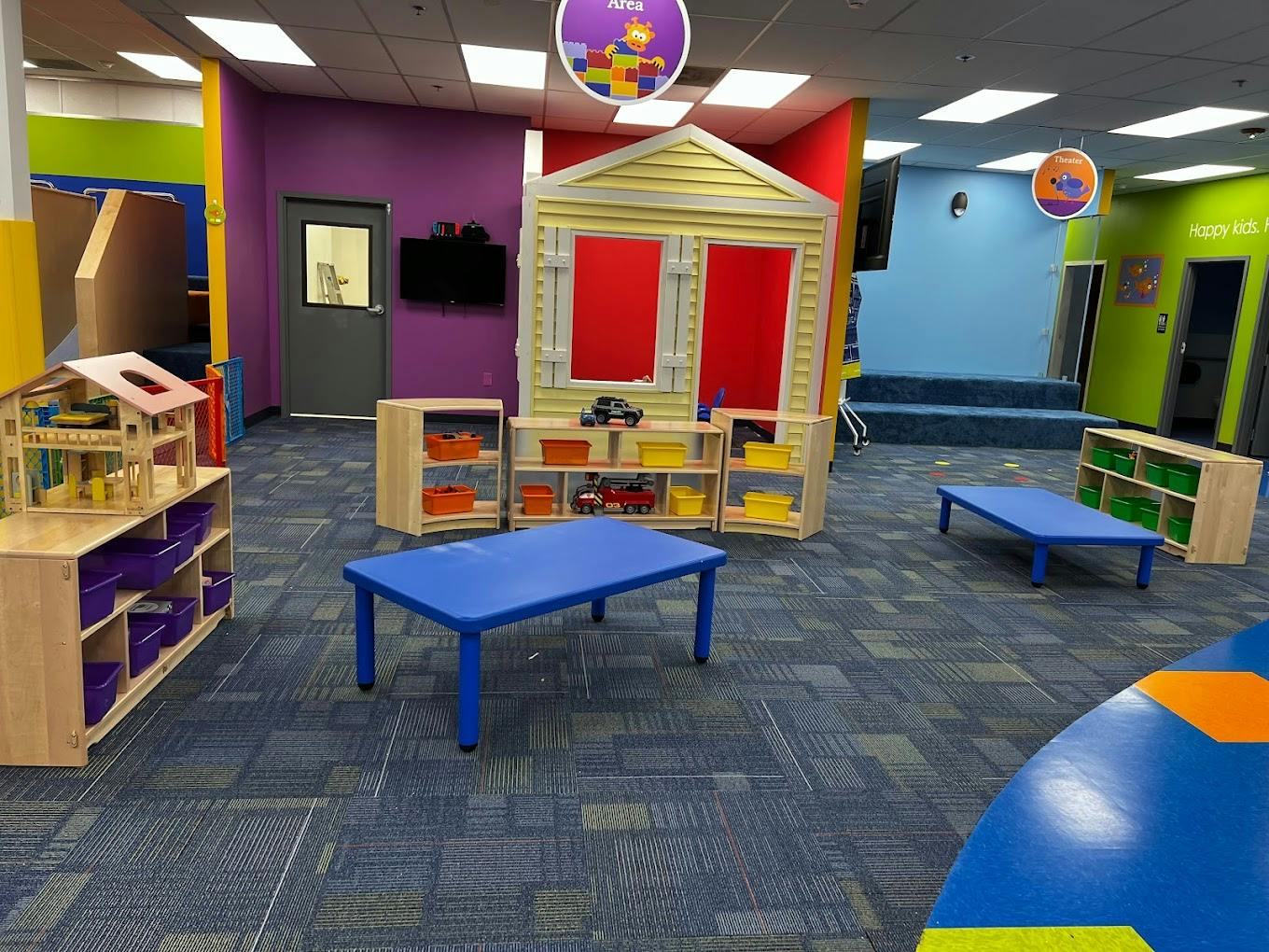 Playroom with small tables, shelves, and a playhouse