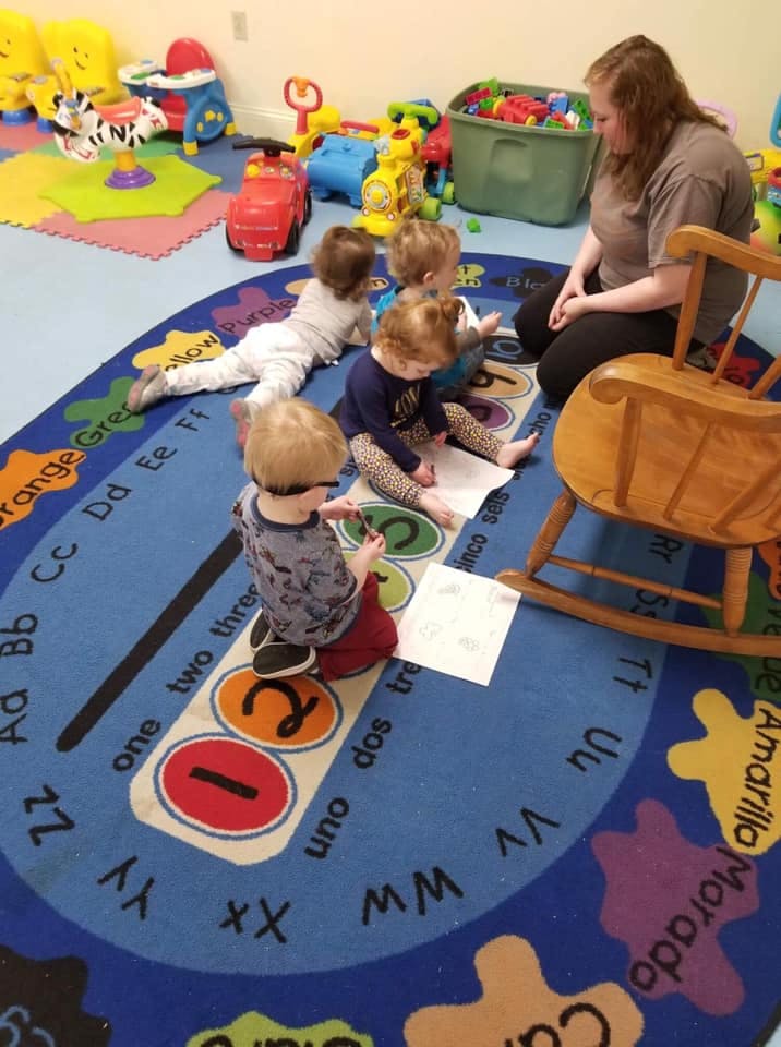 Adult and multiple children sitting on a rug with papers