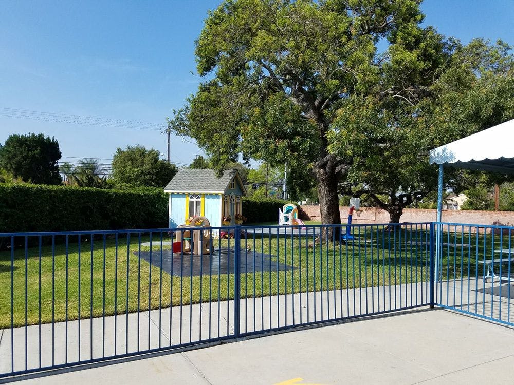 Playground with a small playhouse and a blue fence