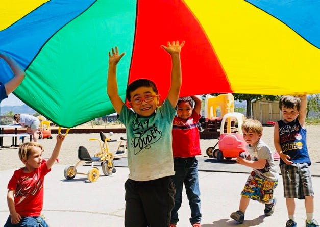 Children playing with a colorful parachute
