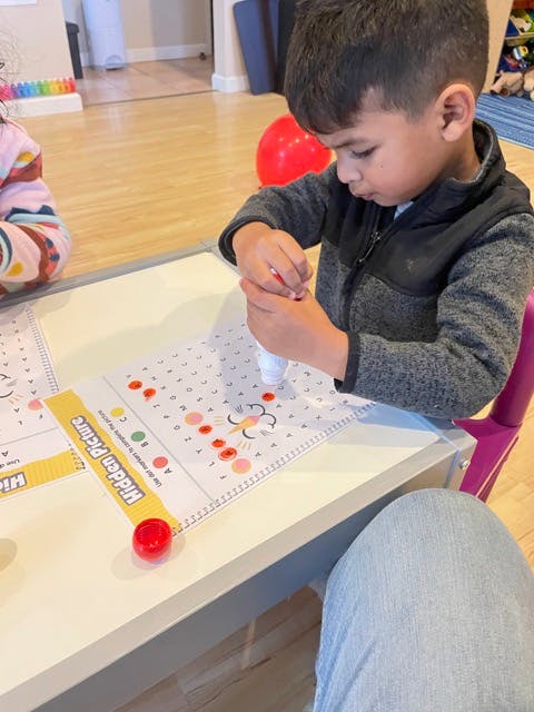 Child using a dot marker on a paper with a hidden picture activity