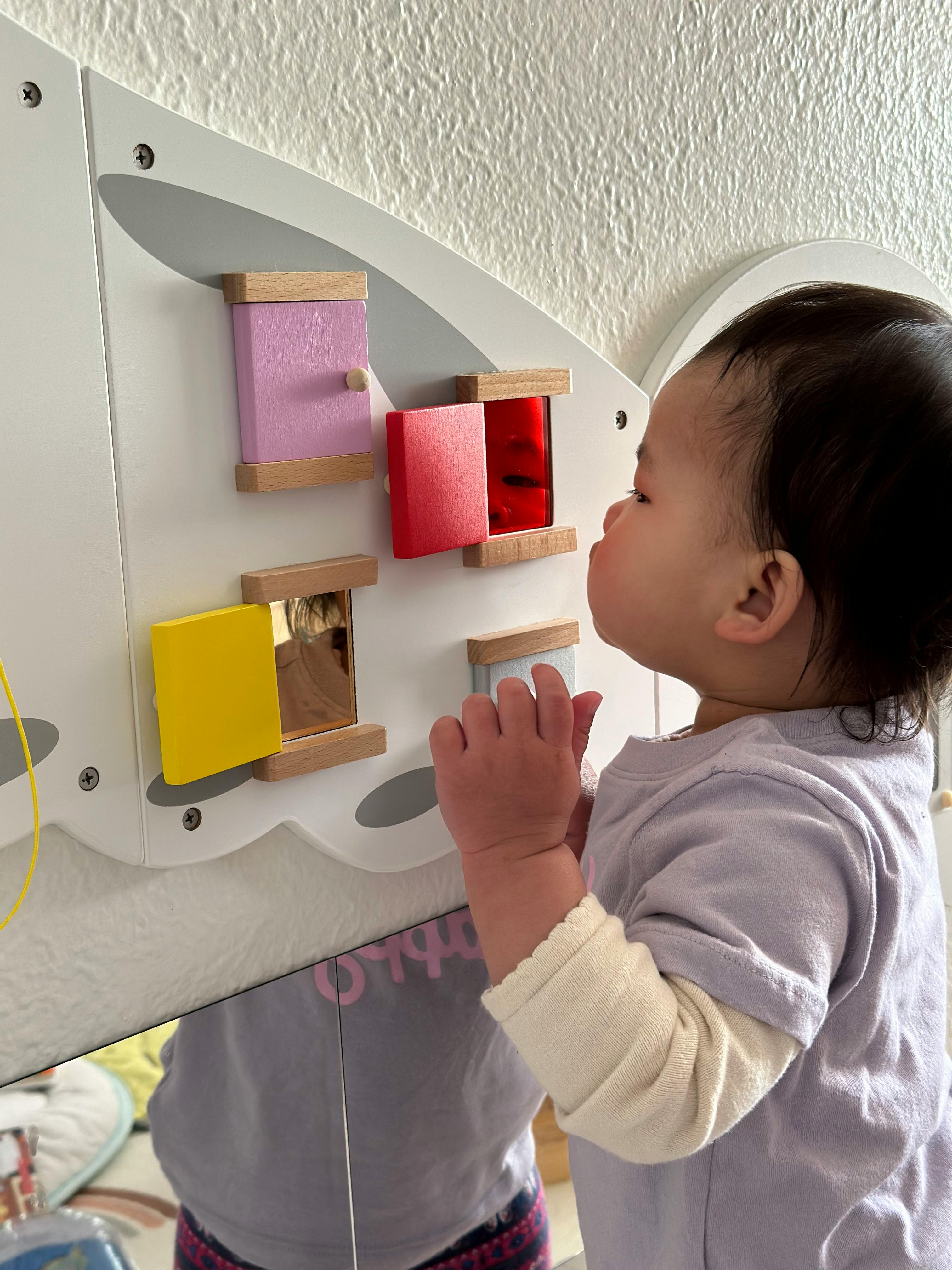 Child looking at a wall-mounted activity board with colorful flaps