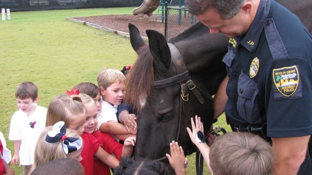Police officer and children petting a horse