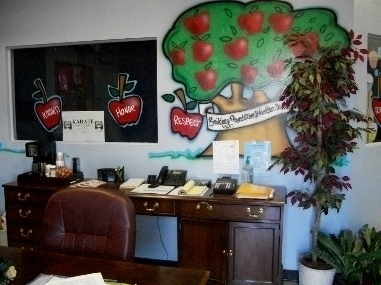 Desk with office equipment and a wall mural of an apple tree