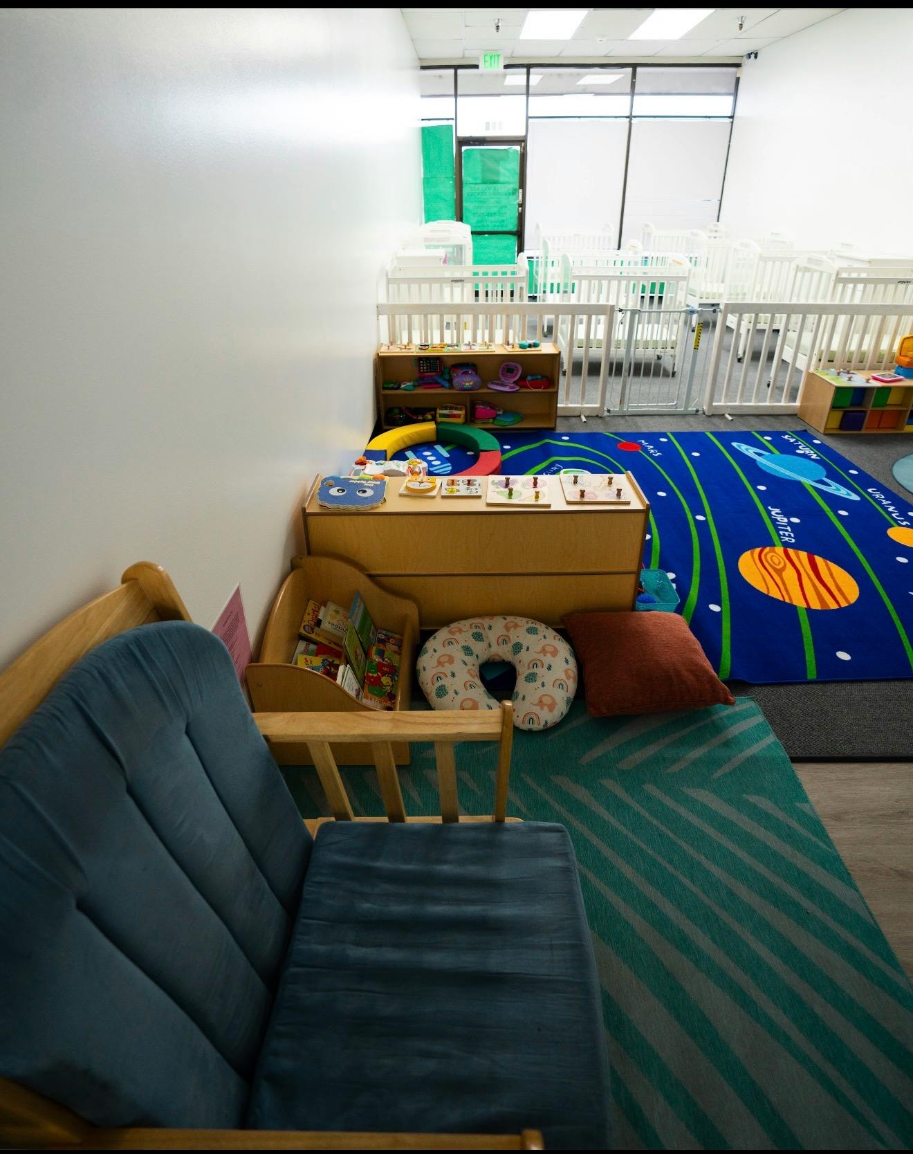 Childcare room with baby cribs and a solar system themed rug