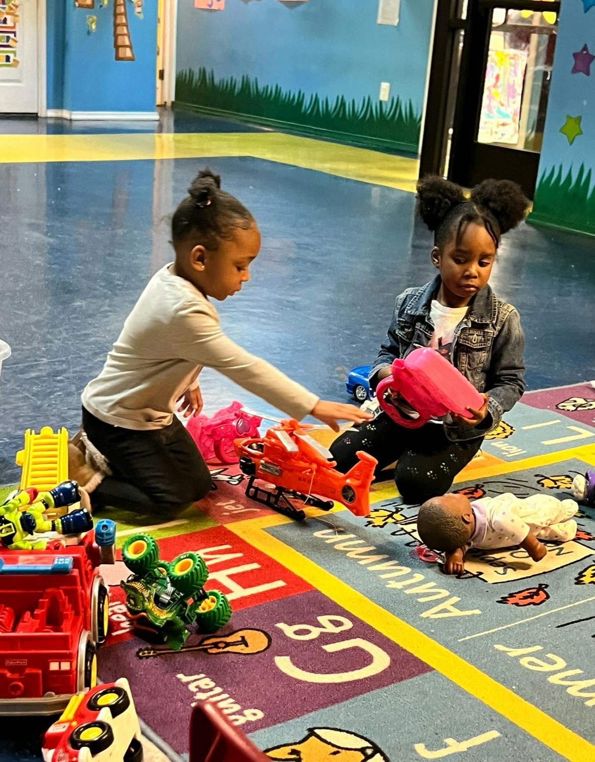 Two children playing with toys on a colorful rug