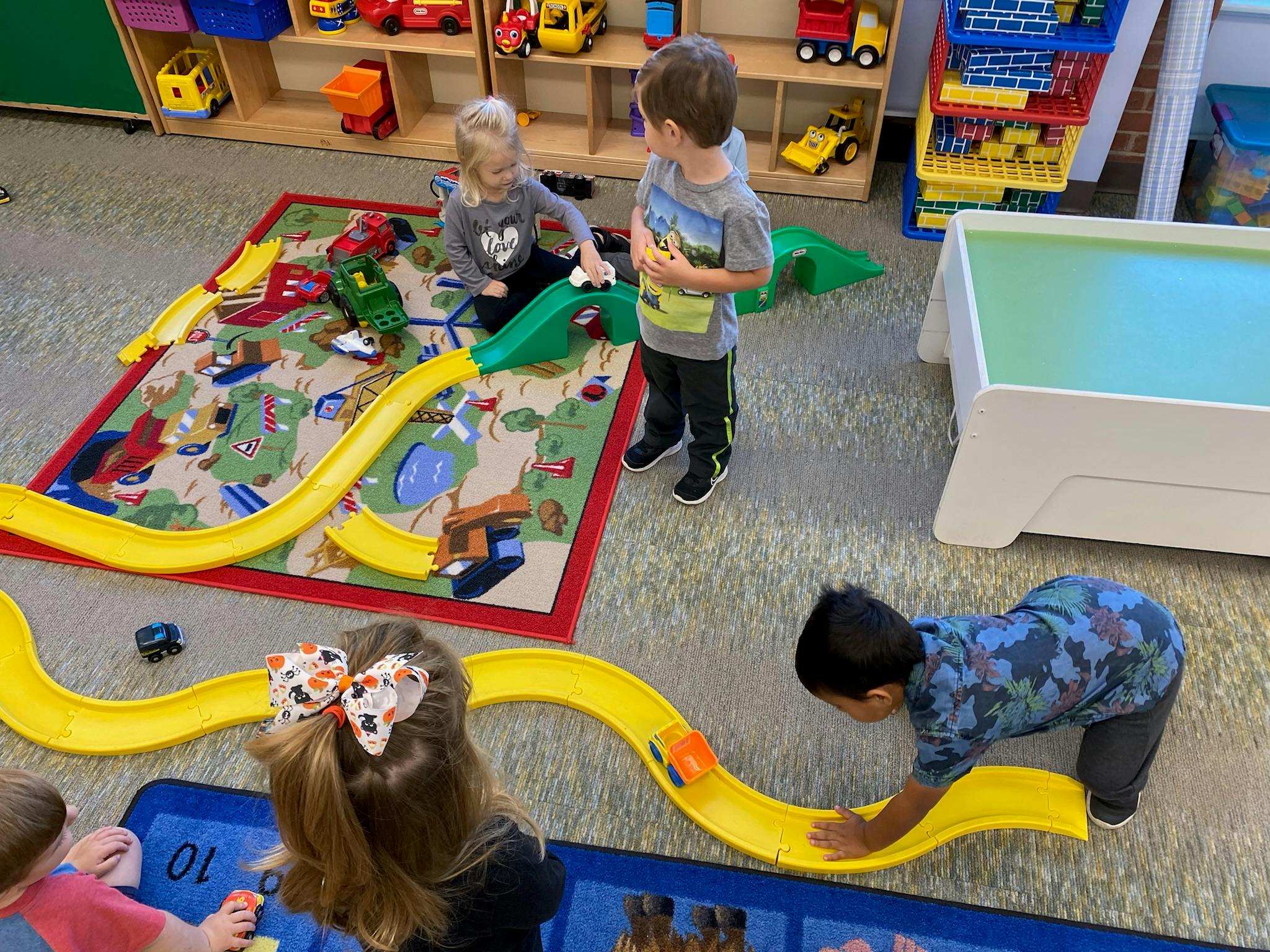 Children playing with toy cars on a track and rug