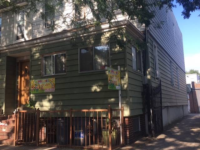 Side of a house with green siding and a wooden fence