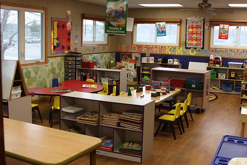 Classroom with tables, chairs, and shelves with learning materials