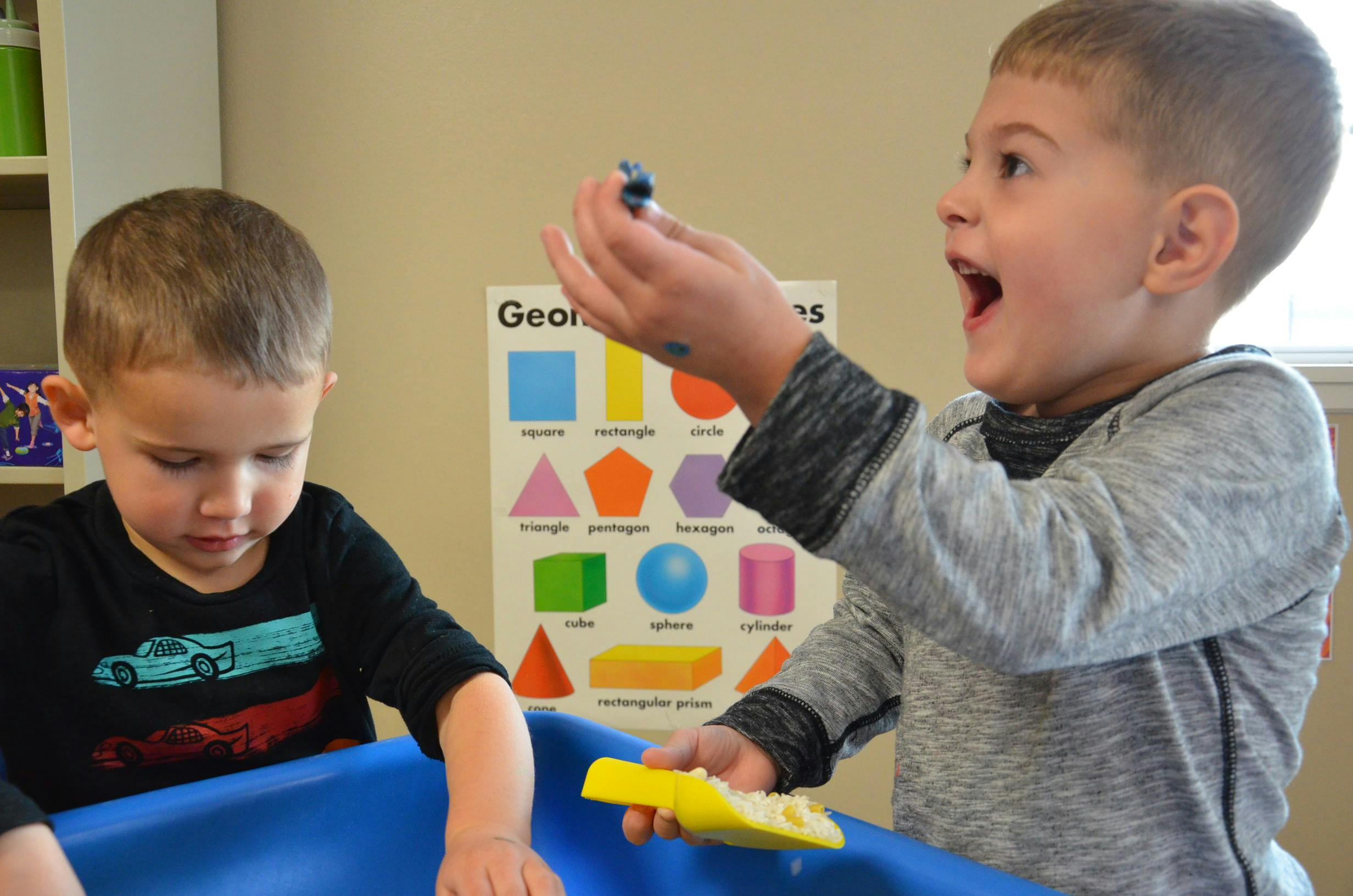 Two children playing with toys in a blue bin