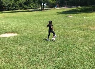 Child playing soccer in a grassy field