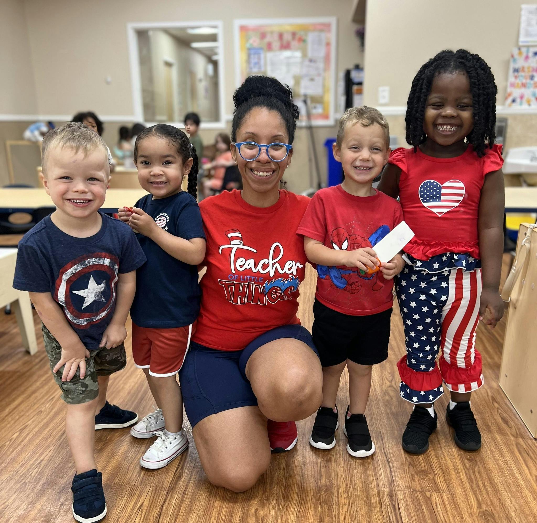 Person kneeling with four children standing around them