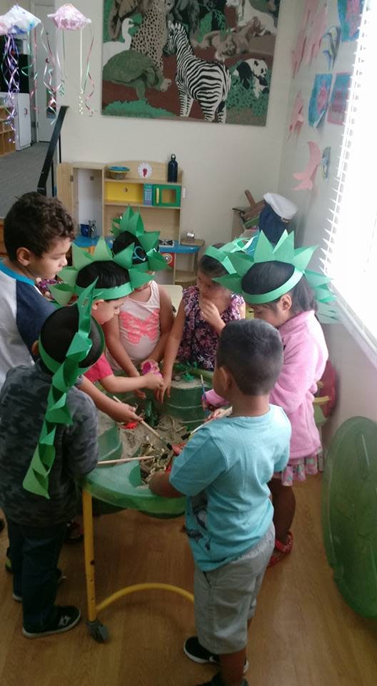 Children wearing green paper crowns playing around a table