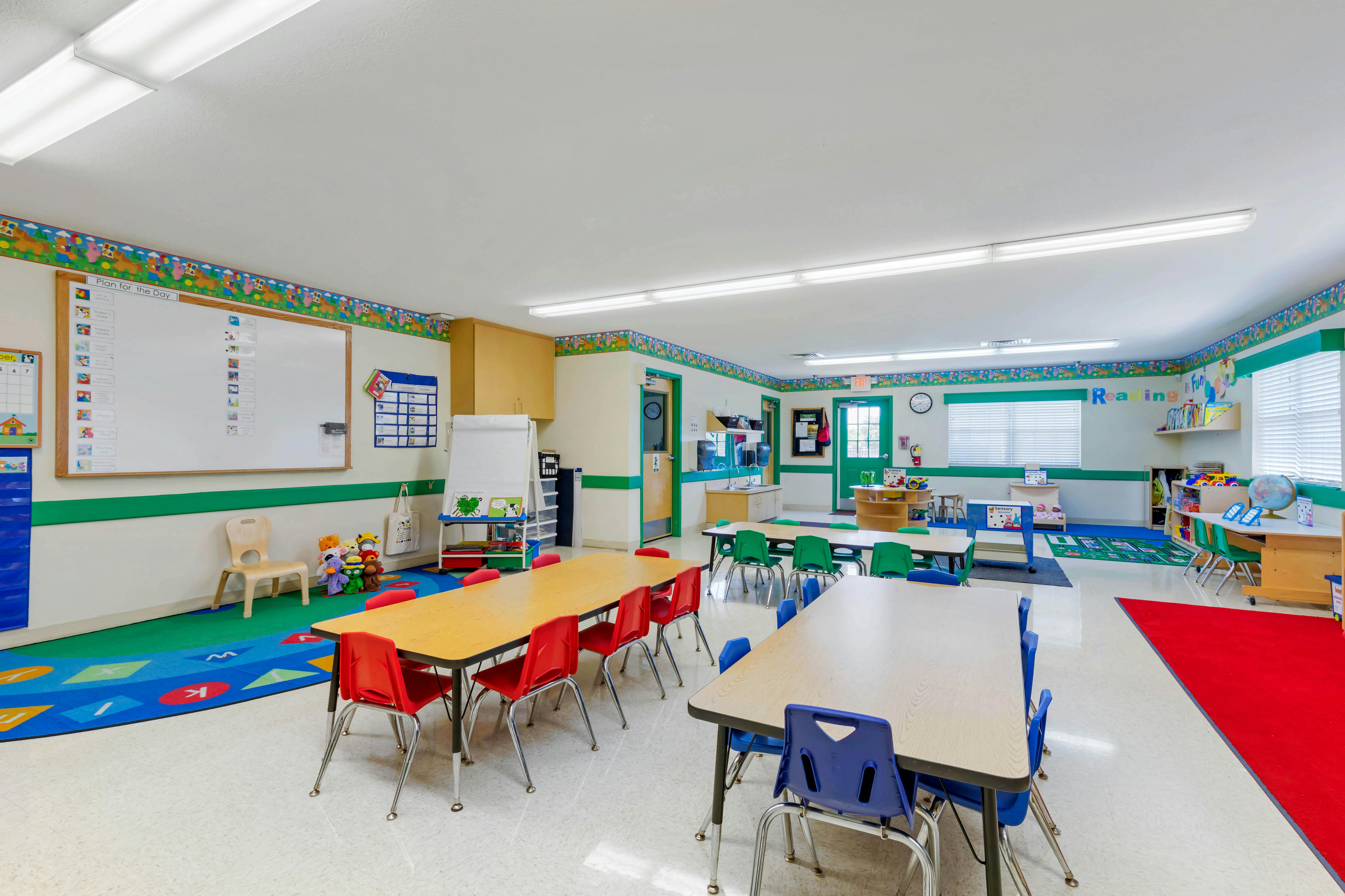 Empty preschool classroom with small tables and chairs