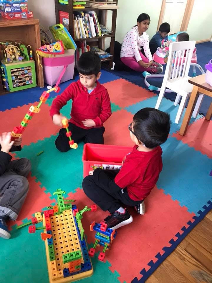 Children playing with building toys on a colorful mat