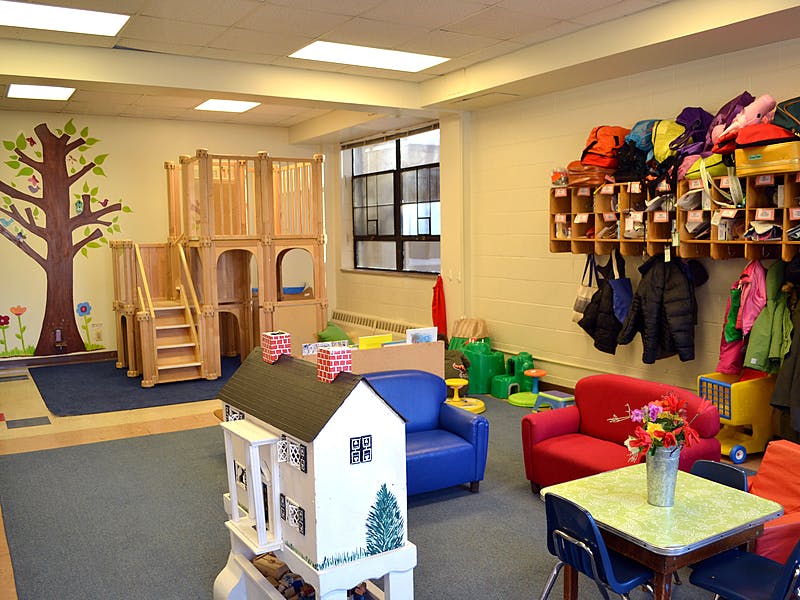 Playroom with wooden play structure, dollhouse, and small furniture